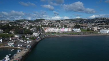 Paignton, Torbay, Güney Devon, İngiltere: İHA Paignton limanında demirlemiş teknelerin yanında uçar ve Paignton Green 'e doğru deniz kenarındaki otelleri ve gezinti güvertesiyle ilerler. Paignton, İngiltere 'de popüler bir tatil ve turizm beldesidir..