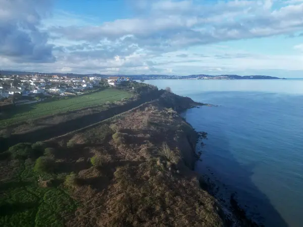 stock image Armchair Cove, Torbay, South Devon, England: DRONE VIEW: The view looking northwards to the seaside town of Torquay from Armchair Cove; to the left is the Torbay Steam Railway track. Torbay is a popular UK holiday destination.