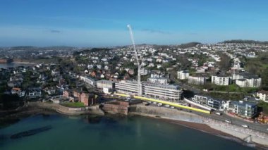 Torquay, Torbay, Güney Devon, İngiltere: DRONE VİEWS: İHA, yeni bir otelin inşaat sahasının ve vincinin etrafında, deniz kenarına yakın daireler çiziyor. Torquay İngiltere 'de popüler bir tatil beldesidir (Clip 2).