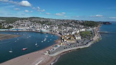 Teignmouth, Güney Devon, İngiltere: DRONE VİEWS: İnsansız hava aracı Teign Nehri 'ni ve Teignmouth kasabasını, rıhtımını ve rıhtımını gösteren denizi çevrelemektedir. Teignmouth hem liman kenti hem de popüler bir İngiliz tatil beldesidir (Clip 1).