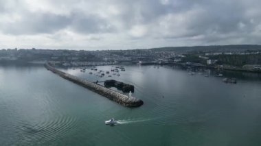 Brixham, Torbay, Güney Devon, İngiltere: DRONE VİEWS: Bir sürat teknesi limandan ayrılır ve denize açılır. Brixham hem İngiltere 'nin büyük bir balıkçılık limanı hem de su sporları ve yelkencilik meraklıları için popüler bir tatil beldesi.).