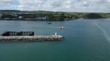 Brixham, Torbay, Güney Devon, İngiltere: DRONE VİEWS: Bir balıkçı teknesi açık denizlere doğru limandan ayrılıyor. Brixham hem İngiltere 'de büyük bir balıkçılık limanı hem de popüler bir yaz tatili merkezidir (Clip 2).