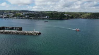 Brixham, Torbay, Güney Devon, İngiltere: DRONE VİEWS: Bir balıkçı teknesi açık denizlere doğru limandan ayrılıyor. Brixham hem İngiltere 'de büyük bir balıkçılık limanı hem de popüler bir yaz tatili merkezidir (Clip 1).