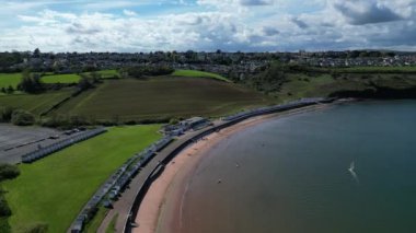 Broadbay, Torbay, Güney Devon, İngiltere: Koyda tek başına sörf yapan bir rüzgar sörfçüsü olarak sahil kulübeleri ve önsahili olan Broadsand Beach. Torbay, günlük gezileri, turistleri ve tatilcileri olan popüler bir İngiliz tatil beldesi..
