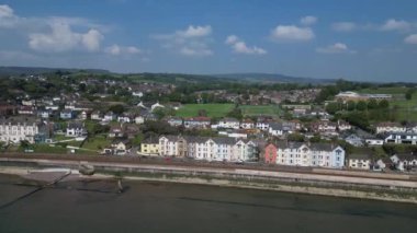 Dawlish, Güney Devon, İngiltere: İHA deniz kenarındaki renkli Viktorya dönemi teras evleri sırasının etrafında daireler çiziyor. Evlerin önünde ana hat demiryolu ve deniz savunma duvarı var. Dawlish, İngiltere 'de popüler bir tatil beldesi..