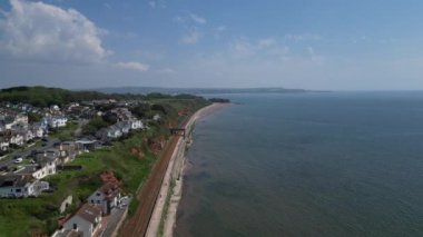 DRONE VİEWS: İHA doğuya, teraslı evlerin, ana demiryolu raylarının ve kumlu plajların üzerinden Dawlish şehir merkezinden uzağa uçuyor. Dawlish İngiltere 'de popüler bir tatil beldesidir (Clip 2).