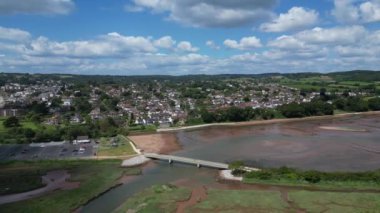 Budleigh Salterton, Devon, İngiltere: DRONE VİEWS: İHA arka planda Jurassic Coast ve Budleigh Salterton 'ı gösteren nehir samuru üzerinde bir köprü etrafında daireler çiziyor. Jurassic Coast popüler bir İngiltere turizm merkezidir (Clip 3).