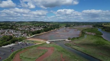 Budleigh Salterton, Devon, İngiltere: DRONE VİEWS: Arka planda Budleigh Salterton kasabasını gösteren Otter Nehri üzerindeki bir köprünün etrafında dönüyor. Kasaba, popüler bir İngiltere turizm merkezi olan Jurassic Coast 'ta yer almaktadır (Clip 2).