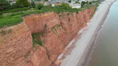 Budleigh Salterton, Doğu Devon, İngiltere: DRONE VİEWS: Dünya Mirası Sahası 'nın bir kısmını oluşturan kırmızı kumtaşı uçurumları ve Budleigh Salterton kasabası. Jurassic Coast, İngiltere 'de popüler bir turizm merkezidir (Clip 2).