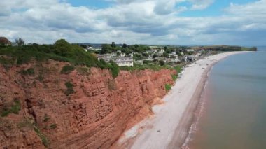 Budleigh Salterton, Doğu Devon, İngiltere: DRONE VİEWS: Dünya Mirası Sahası 'nın bir kısmını oluşturan kırmızı kumtaşı uçurumları ve Budleigh Salterton kasabası. Jurassic Coast popüler bir İngiltere turizm merkezidir (Clip 1).
