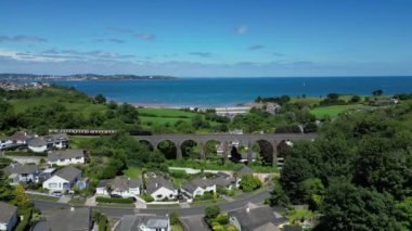 Broadsand, Güney Devon, İngiltere: DRONE VİEWS: Torbay Buhar Demiryolu hattında bir buhar treni viyadük hattını geçer; İHA Broadsand plajına doğru devam eder. Torbay çok çeşitli turistik yerleri olan popüler bir İngiltere tatil beldesidir..