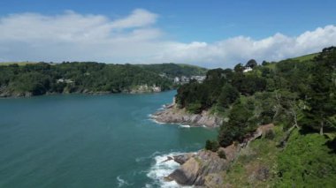 River Dart, Güney Devon, İngiltere: DRONE VİEWS: İHA, Dart Nehri 'nin ağzındaki engebeli kıyı şeridini botlarla ve uzakta Dartmouth kasabasıyla çevreledi. Dartmouth İngiltere 'de popüler bir tatil ve yelkencilik merkezidir (Clip 3).