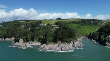 River Dart, Güney Devon, İngiltere: DRONE VİEWS: İHA, Dart Nehri 'nin ağzındaki engebeli kıyı şeridini botlarla ve uzakta Dartmouth kasabasıyla çevreledi. Dartmouth İngiltere 'de popüler bir tatil ve yelkencilik merkezidir (Clip 2).