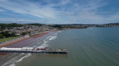 Paignton, Torbay, Güney Devon, İngiltere: DRONE ViEWS: Paignton Pier yaz günışığında; Pier 1879 yılında Kraliçe Victoria 'nın saltanatı sırasında tamamlandı. Paignton, birçok farklı turizm merkeziyle popüler bir İngiltere tatil beldesidir (Clip 1).