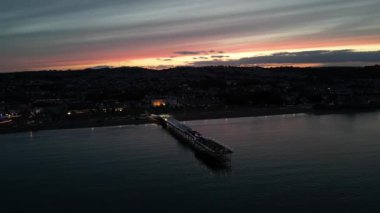 Paignton, Torbay, Güney Devon, İngiltere: DRONE ViEWS: Günbatımında Paignton Pier; Pier 1879 yılında Kraliçe Victoria 'nın saltanatı sırasında tamamlandı. Paignton, birçok farklı turizm merkeziyle popüler bir İngiltere tatil beldesidir (Clip 2).