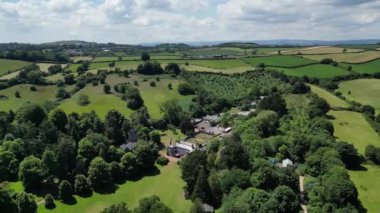 Cockington, Torbay, Güney Devon, İngiltere: DRONE VİEWS: Cockington Park 'ta Cockington Court, St George ve St Mary Church solda. Torbay, kırsal bölgeleri de dahil olmak üzere pek çok eğlencesi olan popüler bir İngiltere tatil beldesidir (Clip 1).