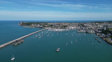 Brixham, Torbay, Güney Devon, İngiltere: DRONE VİEWS: İnsansız hava aracı, Brixham dış limanında demirlemiş tekneleri ve arka plandaki deniz fenerini gösteriyor. İngilizler hem büyük bir balıkçılık limanı hem de İngiltere 'nin popüler tatil beldesidir..