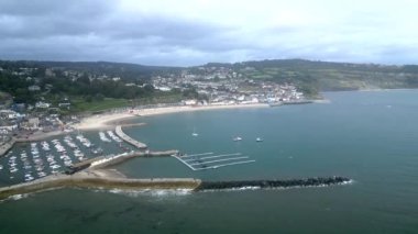 Lyme Regis, Dorset, İngiltere: DRONE VİEWS: İHA limana ve Cobb olarak bilinen ünlü duvarına doğru uçar; Lyme Regis, edebiyat ve film bağlantılarıyla ünlü, Jurassic Coast 'ta popüler bir İngiliz turizm merkezidir..