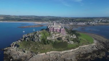 St Michael 's Mount, Cornwall, İngiltere: DRONE VİEWS: St Michael' s Mount ile kıyı şeridi Marazion 'a doğru bakmaktadır; alçak gelgitte bir geçit adayı Marazion' a bağlar. St Michael Dağı popüler bir İngiltere turizm merkezidir (Clip 2).