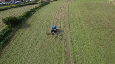 Broadbay, Torbay, Güney Devon, İngiltere: DRONE VİEWS: İHA, sürülen bir tarlada çimleri biçen bir traktörün kuş bakışı görüntüsünü verir. Devon, İngiltere 'de popüler bir tatil beldesidir ve tarım ve çiftlik hayvancılığıyla ünlüdür (Clip 3).
