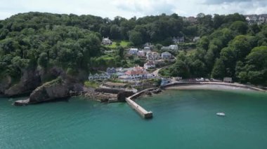 Babbacombe, Güney Devon, İngiltere: DRONE VİEWS: Babbacombe liman duvarı ve sahile bakan mülkler etrafında döner. Babbacombe güzel kıyı şeridiyle tanınan popüler bir İngiltere tatil beldesidir (Clip 2).