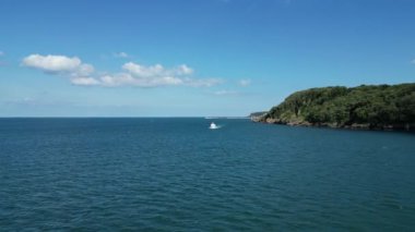 Elberry Cove, Torbay, Güney Devon, İngiltere: DRONE VieWS: Arkaplanda Brixham limanı, turistlerin yaklaştığı bir turist botu olarak kıyı şeridine yakın uçar. Güney Devon, İngiltere 'nin popüler tatil beldesidir..