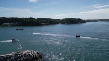 Brixham, Torbay, Güney Devon, İngiltere: DRONE VİEWS: İnsansız hava aracı Brixham dışındaki deniz fenerini geçerek limana giren ve çıkan teknelere doğru uçuyor. Brixham büyük bir balıkçılık limanı ve İngiltere 'de popüler bir tatil beldesi..