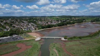 Budleigh Salterton, Doğu Devon, İngiltere: DRONE VİEWS: Budleigh Salterton ile nehir samuru nehri kıyısı; insansız hava aracı kamerası nehrin üzerindeki bir köprünün tepesine doğru eğilir. Jurassic Coast, İngiltere 'de popüler bir turizm merkezidir (Clip 2).