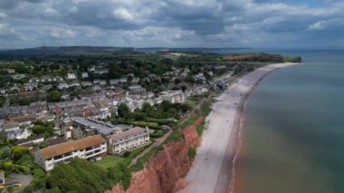 Budleigh Salterton, Doğu Devon, İngiltere: DRONE VİEWS: Dünya Mirası Jurassic Sahili 'nin bir kısmını oluşturan kırmızı kumtaşı uçurumları; B / g' deki Budleigh Salterton kasabası. Jurassic Coast, İngiltere 'de popüler bir turizm merkezidir (Clip 2).