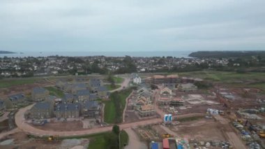 Paignton, Torbay, Güney Devon, İngiltere: DRONE ViEWS: İnsansız hava aracı White Rock yakınlarındaki yeşil kuşak arazisinde yapım aşamasındaki yeni bir konut inşaatı etrafında daireler çiziyor. Paignton, İngiltere 'de birçok turistik merkezi bulunan popüler bir tatil beldesidir (Clip 2).