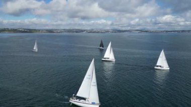 Brixham, Torbay, Güney Devon, İngiltere: DRONE VİEWS: Yatlar yıllık Brixham 'dan Dartmouth yat yarışına katılmak için toplanıyor. Torbay popüler bir İngiltere tatil beldesi ve su sporları ve yelkencilik meraklıları mıknatısıdır (Clip 2).