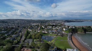 Goodrington Sands, Torbay, Güney Devon, İngiltere: DRONE ViEWS: İHA Young 's Park' a doğru uçuyor ve Roundham Head kayıkçı göllerini ve Goodrington Sands 'i gösteriyor; Paignton Pier b / g' de. Torbay popüler bir İngiltere tatil beldesidir (Clip 1).