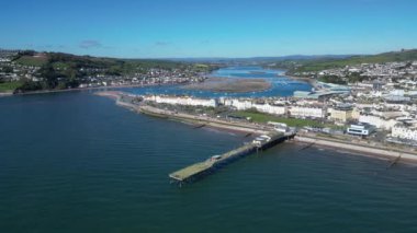 Teignmouth, Güney Devon, İngiltere: DRONE VİEWS: İHA arka planda Teign Nehri ile Grand Pier ve Teignmouth sahil şeridinde daireler çiziyor. Teignmouth hem bir liman şehri hem de popüler bir İngiltere tatil beldesidir (Clip 2).