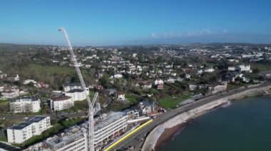 Torquay, Torbay, Güney Devon, İngiltere: DRONE VİEWS: İHA yeni bir otel şantiyesi ve deniz kenarındaki vinci üzerinde yükseliyor. Torbay, İngiltere 'de popüler bir tatil beldesidir ve turist konaklama yerinin yenilenmesinden geçmektedir (Clip 1).