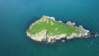 Torquay, Torbay, Devon, İngiltere: DRONE VİEWS: İHA, Torquay tatil beldesi yakınlarındaki büyük bir ada veya kıyı dışı kaya olan Thatcher Kayası 'nın etrafında döner. Torbay popüler bir İngiltere tatil beldesi ve su sporları meraklıları için bir mıknatıstır (Clip 1).