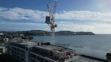 Torquay, Torbay, Güney Devon, İngiltere: DRONE VİEWS: İHA, inşaat halindeki yeni bir otelin üzerinden yükseliyor. Arka planda Torbay denizi ve Torquay kasabası yer almaktadır. Torbay İngiltere 'de popüler bir tatil beldesidir (Clip 3).