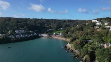 Salcombe, Güney Devon, İngiltere: DROVE VİEWS: İHA pahalı nehir kıyısındaki mülkleri gösteren South Sands plajına doğru uçuyor. Salcombe, İngiltere 'nin en popüler tatil beldesidir ve İngiltere' deki en yüksek ortalama emlak fiyatlarından birine sahiptir (Klip 1).