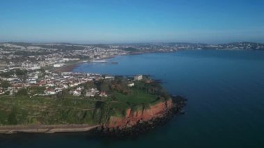 Torbay, Devon, İngiltere: Drone Roundham Head 'in etrafında Paignton, Paignton Pier, Torbay, Torquay ve Thatcher Rock' ı gösteriyor. Torbay popüler bir İngiltere tatil beldesi ve su sporları ve yelkencilik meraklıları mıknatısı (Clip 4).