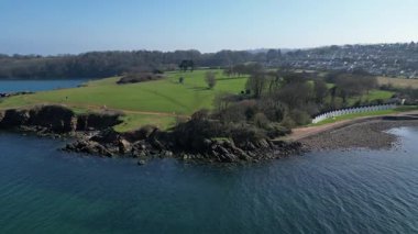 Broadbay, Torbay, Güney Devon, İngiltere: DRONE VİEWS: İHA Broadsand sahilindeki sahil kulübelerini göstermeden önce bir kıyı burnu üzerinde döner ve iner. Torbay, ünlü sahil şeridi nedeniyle popüler bir İngiltere tatil beldesidir (2.).