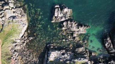 Broadsands, Torbay, South Devon, England: DRONE VIEWS: The drone ascends over coastline rocks and the aquamarine sea. Torbay is a popular UK holiday destination renowned for its beautiful coastline.