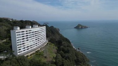 Torbay, Güney Devon, İngiltere: DRONE VİEWS: İnsansız hava aracı arka planda Orestone ile Thatcher Kayası 'na doğru giden bir anakara apartman kompleksinin yanından uçuyor. Torbay İngiltere 'de popüler bir tatil ve emeklilik alanıdır (2.).