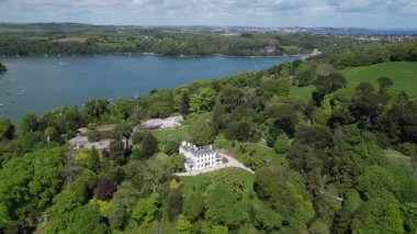 Greenway, River Dart, Devon, İngiltere: DRONE ViEW: Greenway House ve bahçeler, daha önce ünlü suç yazarı Agatha Christie 'ye aitti. Greenway House popüler bir turizm merkezi. Küresel ziyaretçileri çekiyor ve Dart Nehri 'ni gözden kaçırıyor..