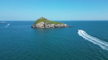 Torbay, Güney Devon, İngiltere: DRONE VİEWS: Bir sürat teknesi Thatcher Kayası 'na doğru yol alır; insansız hava aracı Orestone' u uzaktan ortaya çıkarmak için Kaya 'dan yükselir. Torbay İngiltere 'de popüler bir tatil beldesi..