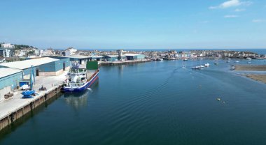 Teignmouth, Güney Devon, İngiltere: DRONE VİEWS: Teign Nehri kıyısındaki kasabanın ticari rıhtımlarına demirlemiş bir gemi. Teignmouth limanı top kilini ihraç eder ve hayvan yemi ve toplamlar ithal eder; aynı zamanda İngiltere 'de popüler bir tatil beldesidir.