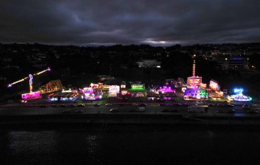 Torquay, Torbay, Güney Devon, İngiltere: DRONE ViEW: Tüm gece boyunca yaz lunaparkında aydınlatılmış sürüş. Torbay, pek çok ziyaretçisi olan popüler bir İngiltere tatil beldesi..