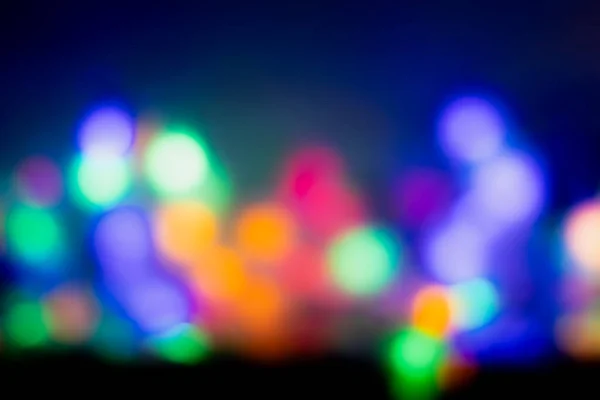 Bulanık arka planda akşam vakti alacakaranlık altında renkli parlayan ışıklar parlıyor.. 