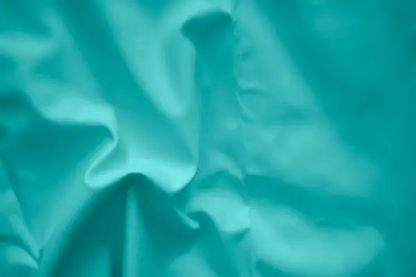 İpek, soyut desenli yeşil saten arkaplanda buruşmuştu. Soyut kumaş duvar kağıdı.