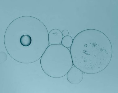 Yeşil-mavi arka planda kabarcıklar oluşturmak için yağ ve su damlacıklarını yeniden yapılandır .