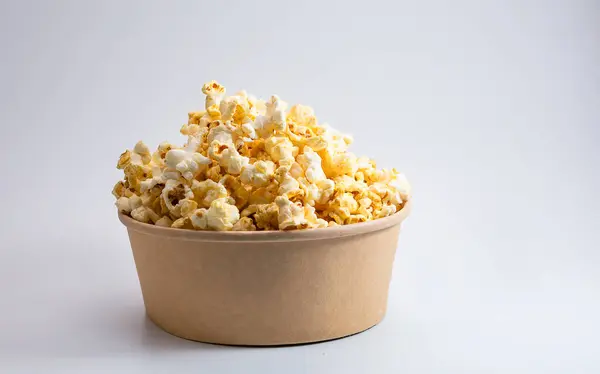 Beyaz arka planda izole edilmiş kağıt kovadaki patlamış mısır. Atıştırmalık.