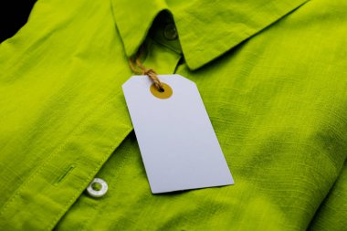 Boş karton etiket fiyat etiketi, yeşil tişörtte arka plan satışı için kahverengi ip eklentisi. Çevre dostu kavram.